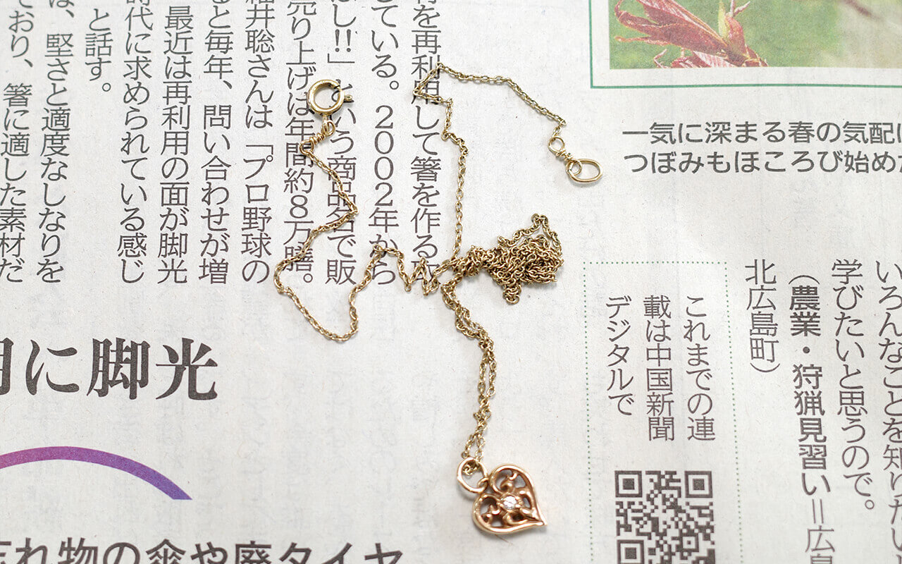 絡まったネックレスを新聞紙の上に置いた写真